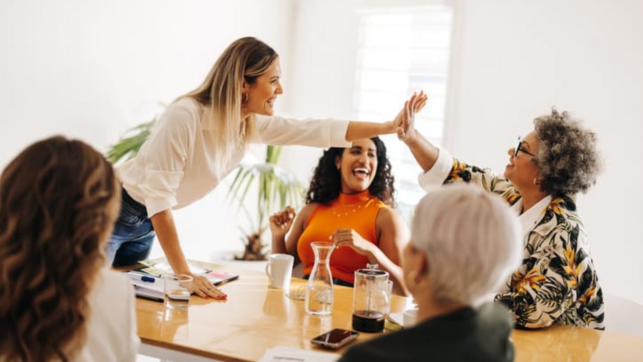Business colleagues high fiving each other in a boardroom
