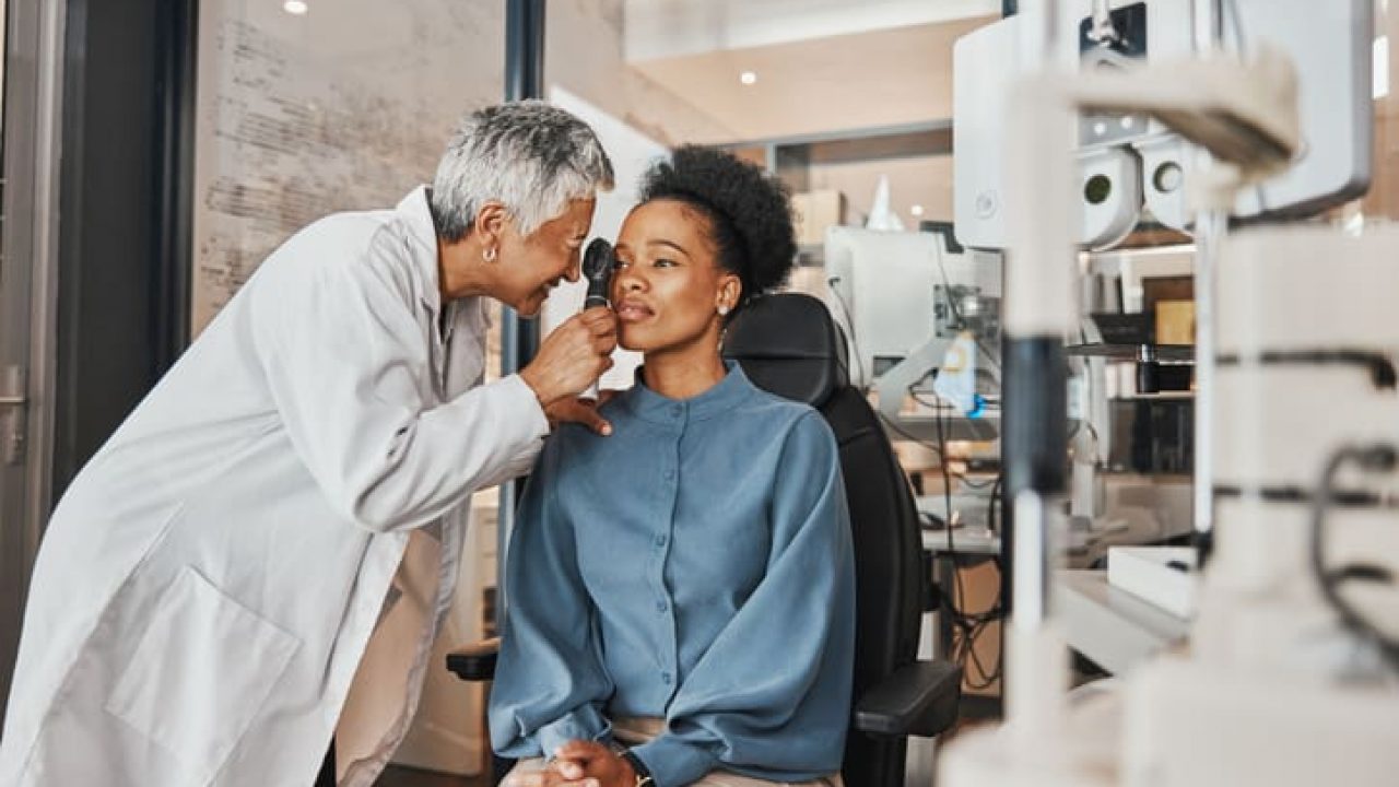 Doctor, vision or black woman in eye exam consultation or assessment for eyesight at optometrist office. Mature or senior optician helping a customer testing or checking iris or retina visual health