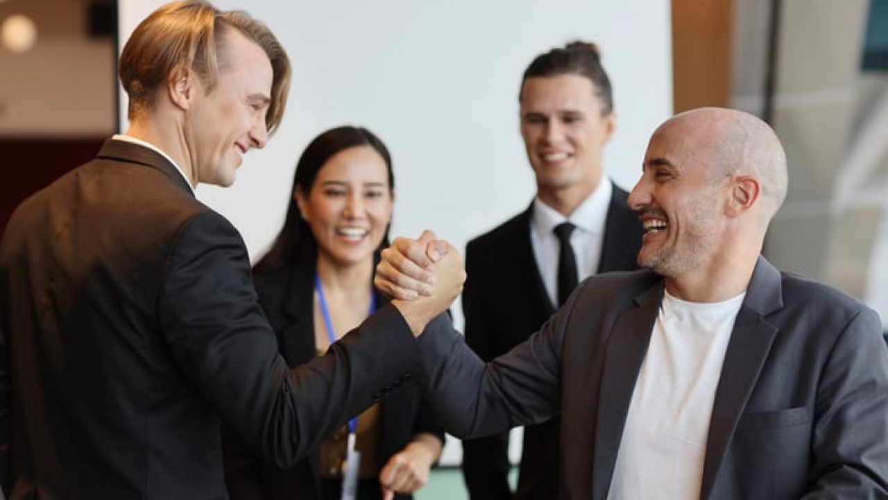 Young multiethnic collaborative process of professional businesspeople arm wrestling after new business contract signed with happy smiling face. Coworker and working together concept