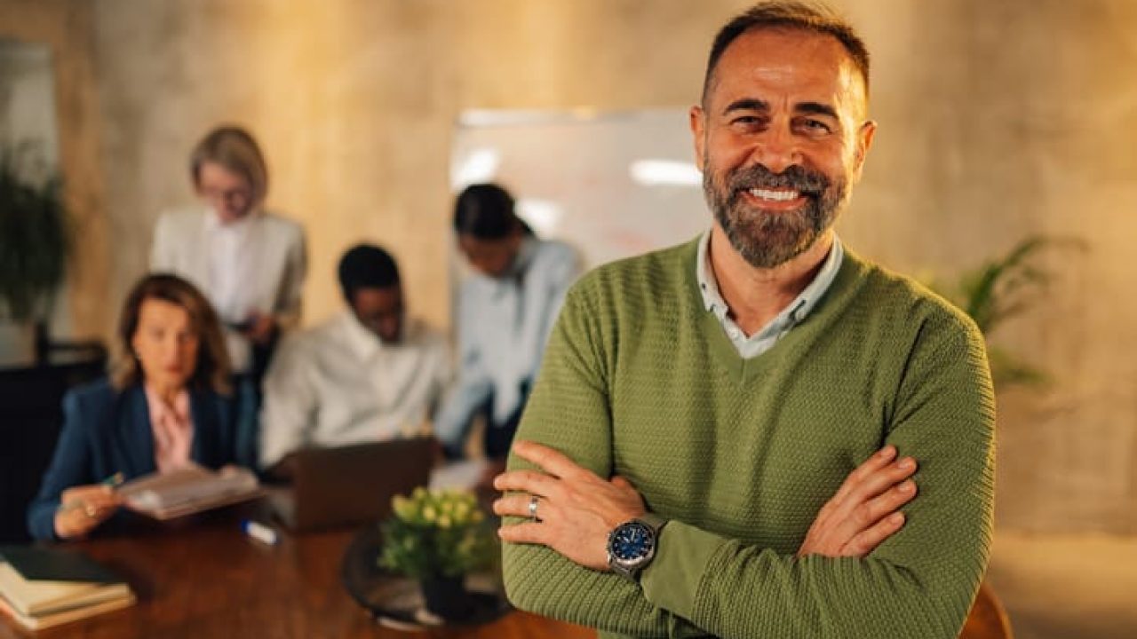 Mature executive posing at boardroom on meeting of interracial team.