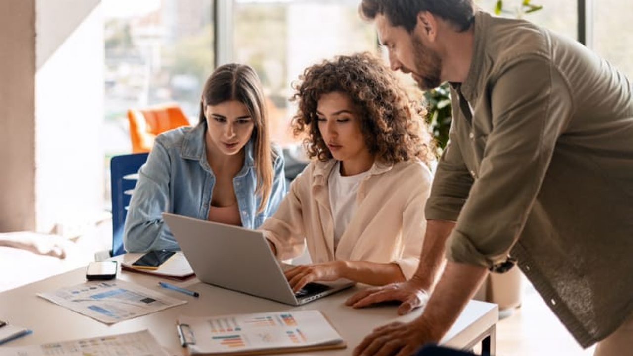 Focused colleagues working together on a laptop in modern office