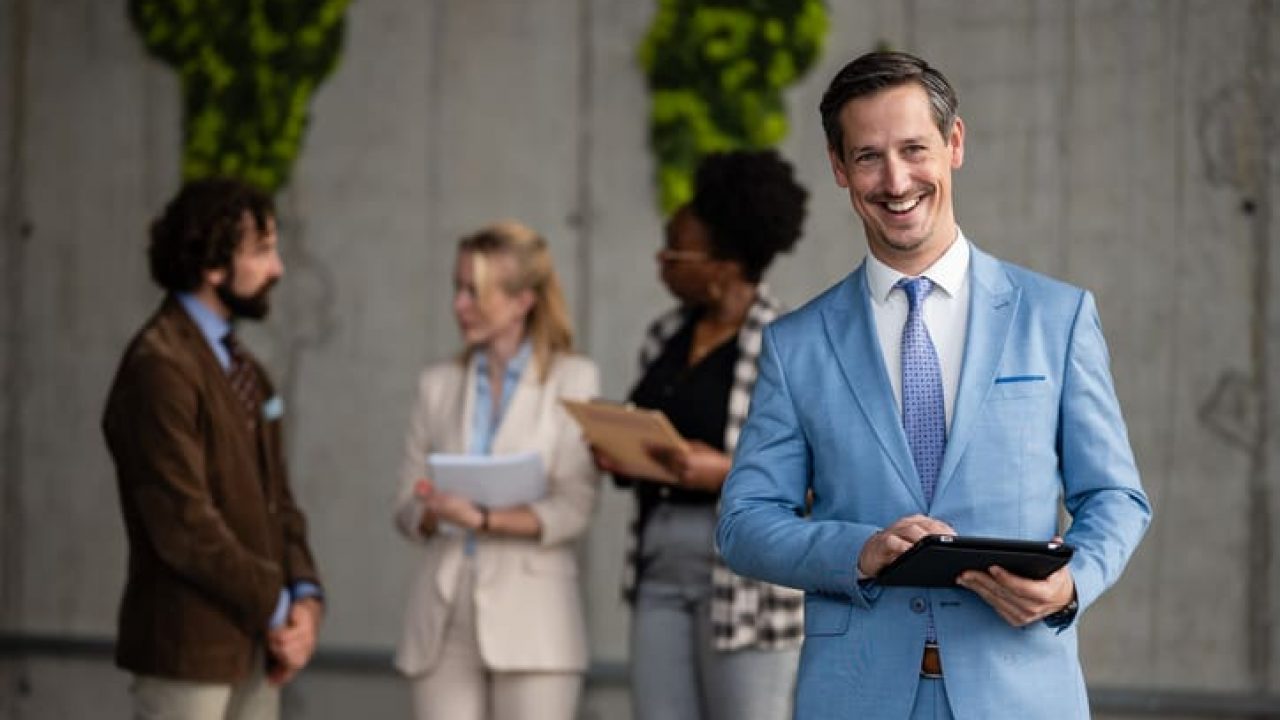 Happy businessman holding tablet while diverse team collaborates